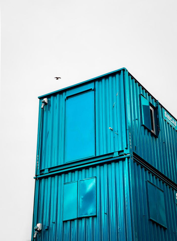 Stacked blue shipping containers with bird in Leeds, England.
